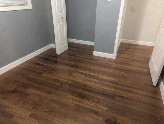 unfurnished bedroom with baseboards, dark wood finished floors, and a closet