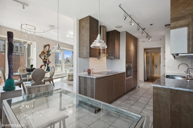 kitchen with light stone countertops, stainless steel oven, black electric cooktop, sink, and pendant lighting