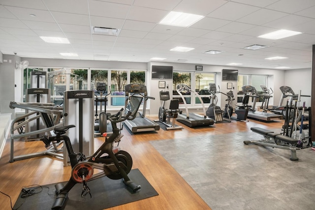 gym with a drop ceiling and wood-type flooring