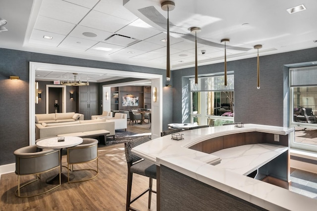 bar featuring wood-type flooring, a raised ceiling, and hanging light fixtures