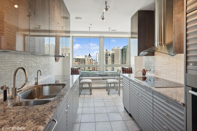 kitchen featuring tasteful backsplash, stone counters, sink, and wall chimney exhaust hood