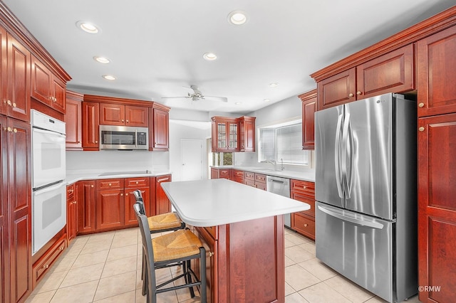 kitchen with appliances with stainless steel finishes, ceiling fan, sink, a center island, and a breakfast bar area