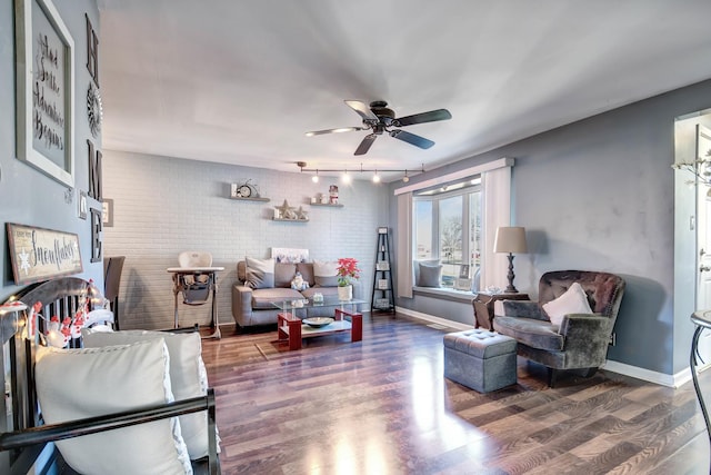 living room featuring ceiling fan, dark wood-type flooring, and brick wall