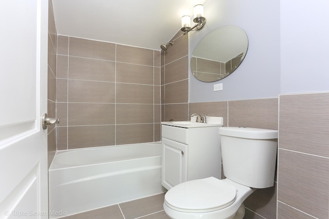 full bathroom with tile patterned floors, vanity, tiled shower / bath combo, tile walls, and toilet