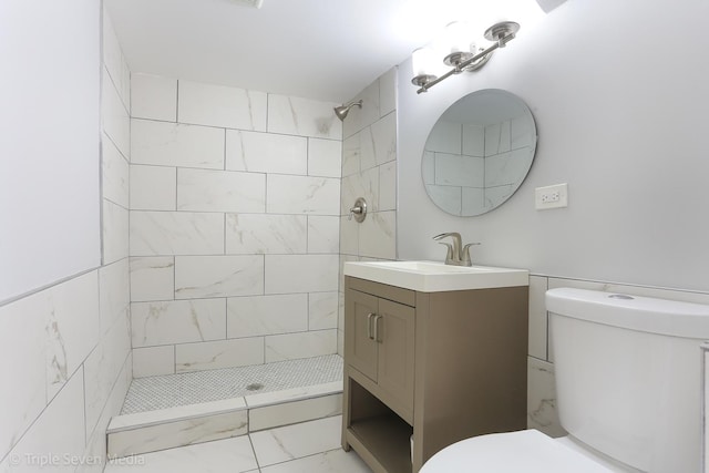 bathroom with vanity, toilet, and a tile shower