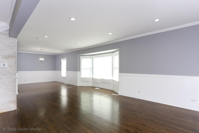 spare room featuring crown molding, dark wood-type flooring, and an inviting chandelier