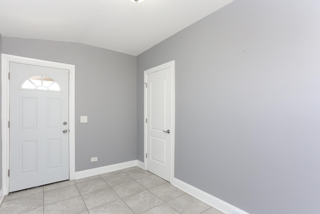 foyer entrance featuring light tile patterned flooring and vaulted ceiling