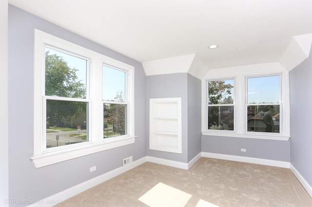 bonus room featuring built in shelves, light colored carpet, plenty of natural light, and lofted ceiling