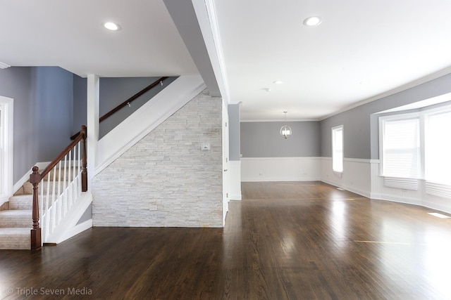 unfurnished living room with dark hardwood / wood-style floors, an inviting chandelier, and crown molding