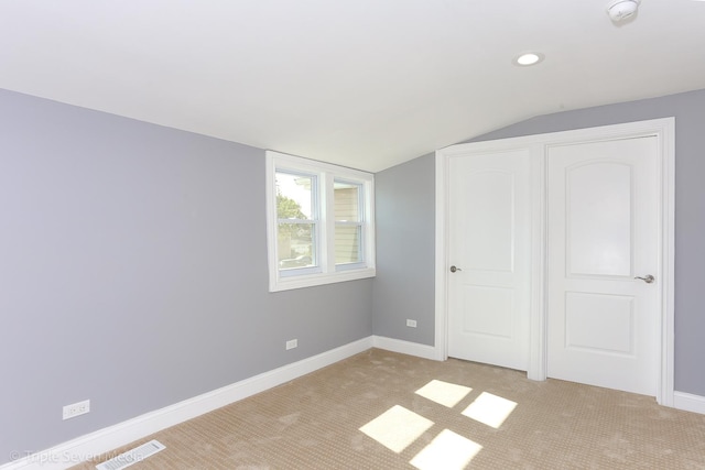 unfurnished bedroom with light carpet and lofted ceiling