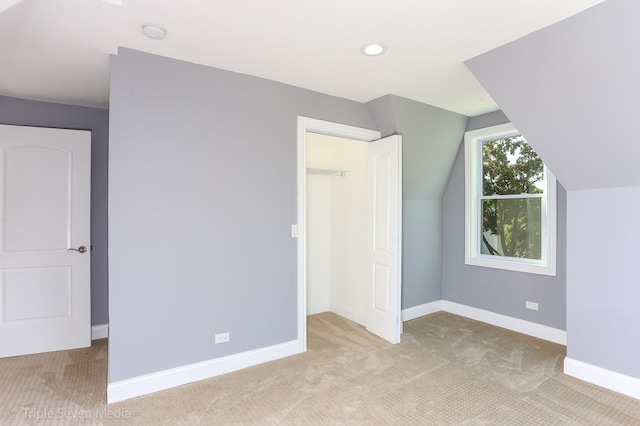 additional living space featuring light carpet and vaulted ceiling