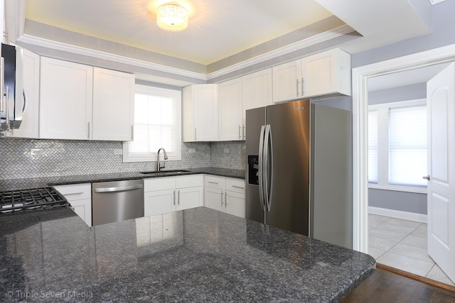 kitchen with white cabinets, sink, dark stone countertops, appliances with stainless steel finishes, and tasteful backsplash