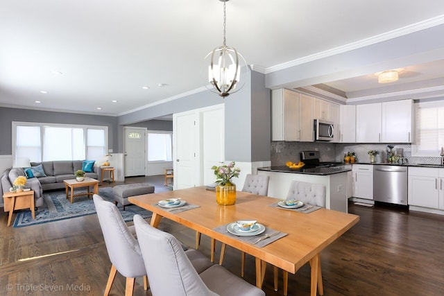 dining area with a healthy amount of sunlight, dark hardwood / wood-style flooring, ornamental molding, and an inviting chandelier