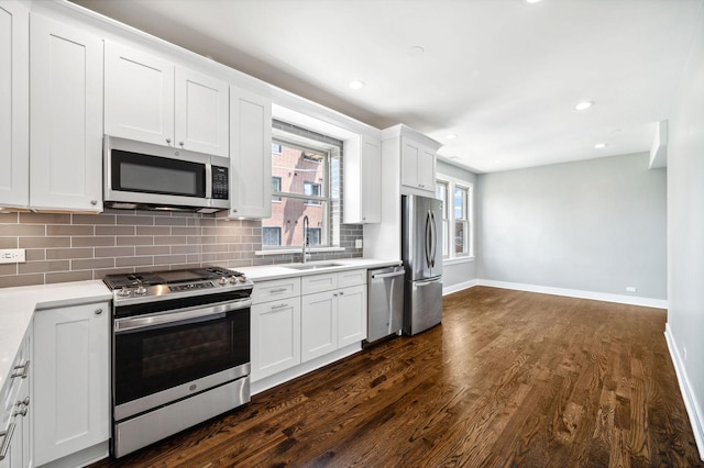 kitchen with sink, white cabinetry, dark hardwood / wood-style flooring, stainless steel appliances, and decorative backsplash