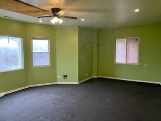 unfurnished room with dark colored carpet and ceiling fan