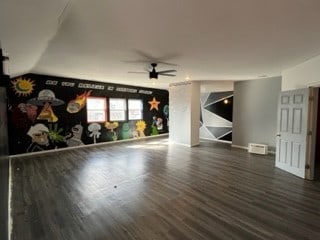 unfurnished living room featuring ceiling fan and dark hardwood / wood-style flooring