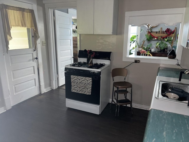 kitchen with gas range gas stove, sink, white cabinets, and dark wood-type flooring