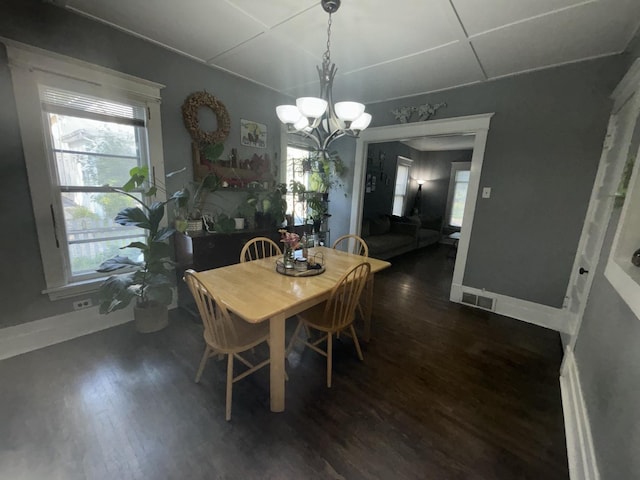 dining space with dark hardwood / wood-style flooring and a notable chandelier