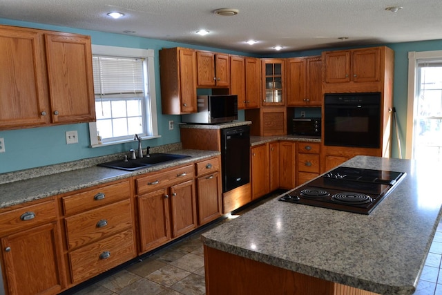 kitchen featuring a kitchen island, black appliances, sink, and a healthy amount of sunlight