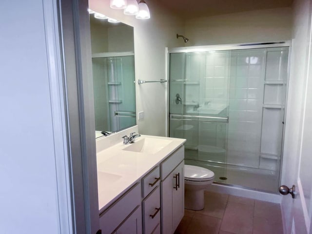 bathroom with tile patterned flooring, vanity, a shower with door, and toilet