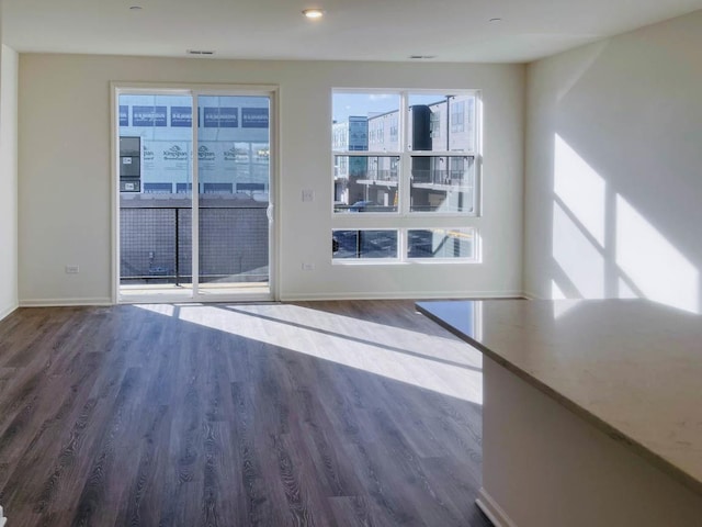 unfurnished living room featuring a healthy amount of sunlight and dark hardwood / wood-style floors