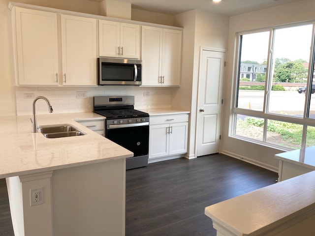 kitchen featuring light stone countertops, sink, stainless steel appliances, decorative backsplash, and white cabinets