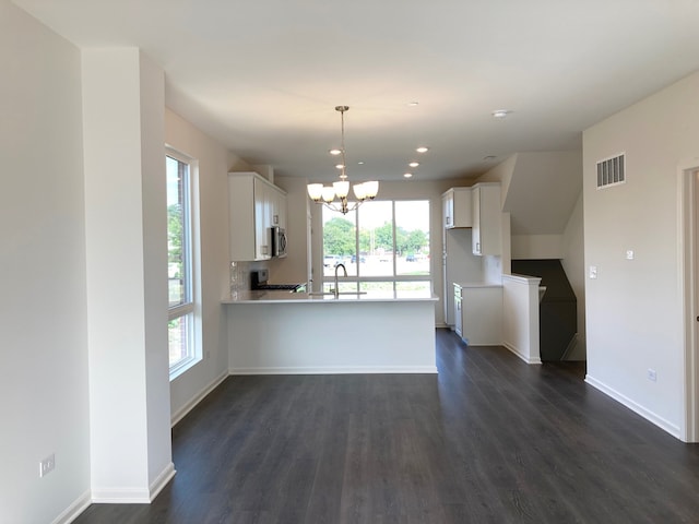 kitchen with kitchen peninsula, white cabinetry, a wealth of natural light, and dark wood-type flooring