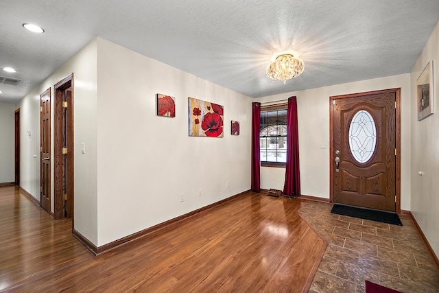 foyer with dark hardwood / wood-style floors, a textured ceiling, and an inviting chandelier