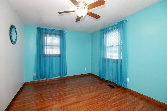 unfurnished room featuring ceiling fan, dark hardwood / wood-style flooring, a textured ceiling, and a wealth of natural light