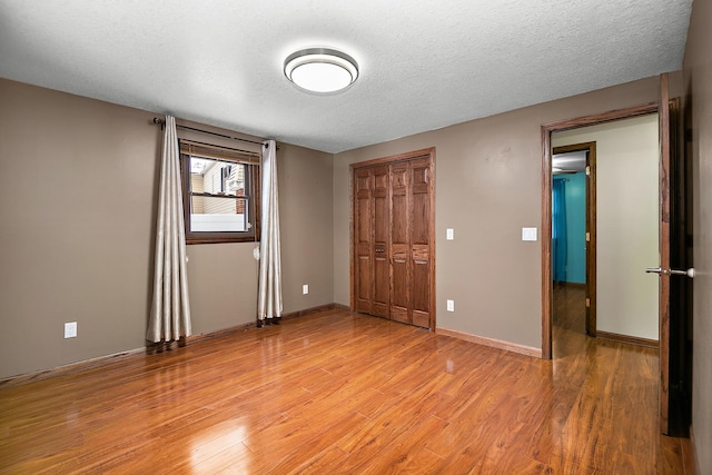 unfurnished bedroom featuring a textured ceiling, light hardwood / wood-style floors, and a closet