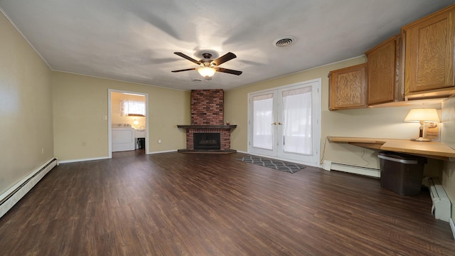 unfurnished living room with a brick fireplace, dark hardwood / wood-style flooring, washer / clothes dryer, and a baseboard radiator