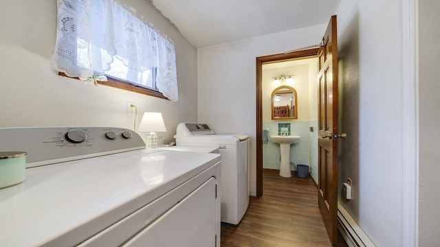 laundry room with dark hardwood / wood-style flooring, baseboard heating, sink, washer and dryer, and tile walls