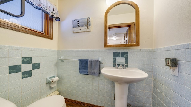 bathroom featuring toilet and tile walls