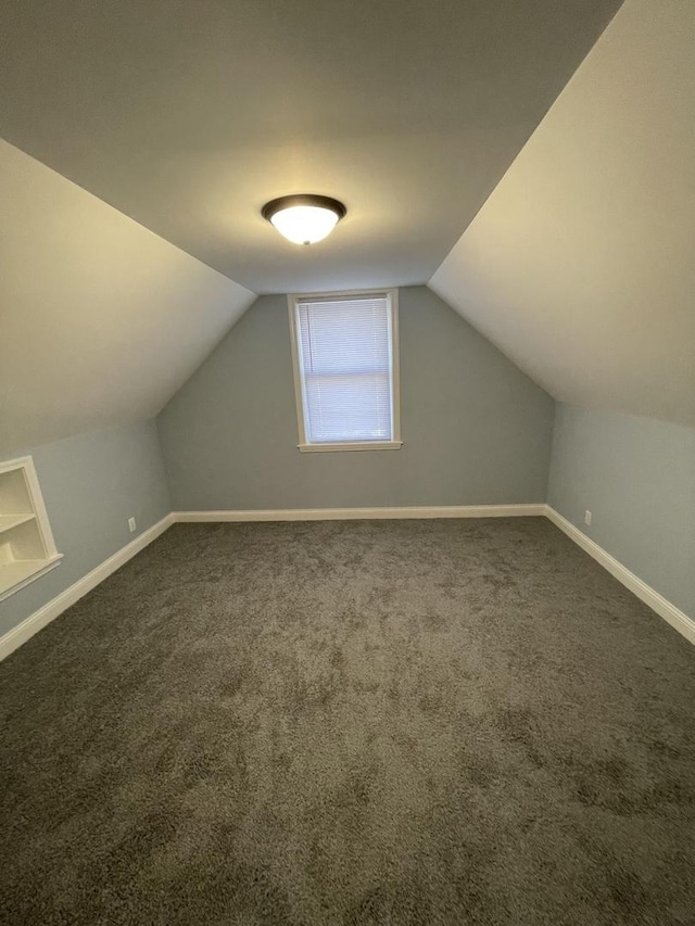 bonus room featuring dark carpet and vaulted ceiling