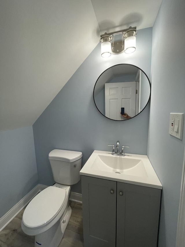 bathroom with hardwood / wood-style flooring, vanity, toilet, and vaulted ceiling