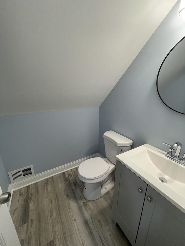 bathroom featuring vanity, toilet, wood-type flooring, and lofted ceiling