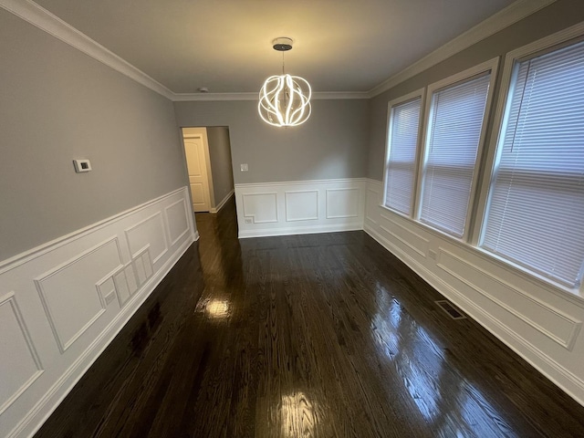 unfurnished dining area featuring dark hardwood / wood-style floors, crown molding, and a notable chandelier