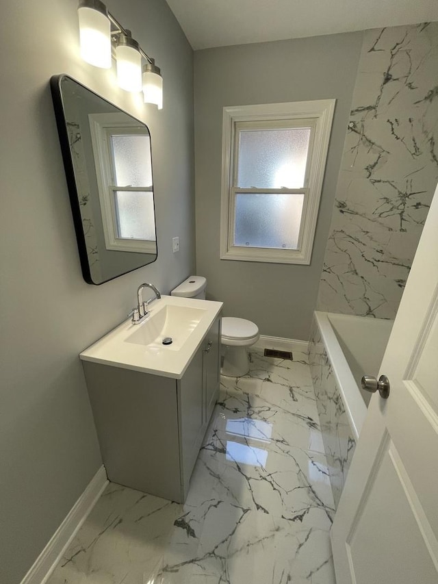 bathroom featuring vanity, toilet, a bathtub, and a healthy amount of sunlight