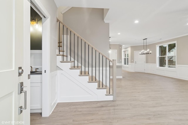 stairs featuring hardwood / wood-style flooring, ornamental molding, and a chandelier