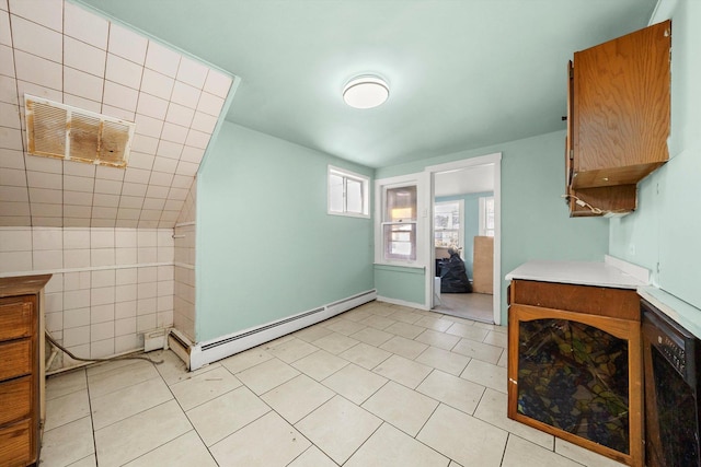 kitchen with light tile patterned floors, baseboard heating, and tile walls