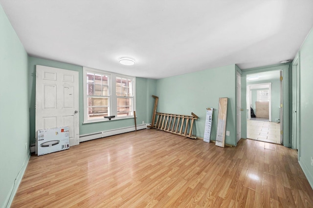 interior space featuring multiple windows, light wood-type flooring, and a baseboard heating unit