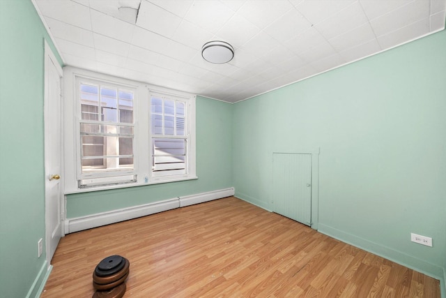 unfurnished room featuring light hardwood / wood-style floors and a baseboard radiator