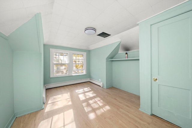 bonus room with light hardwood / wood-style flooring and a baseboard heating unit