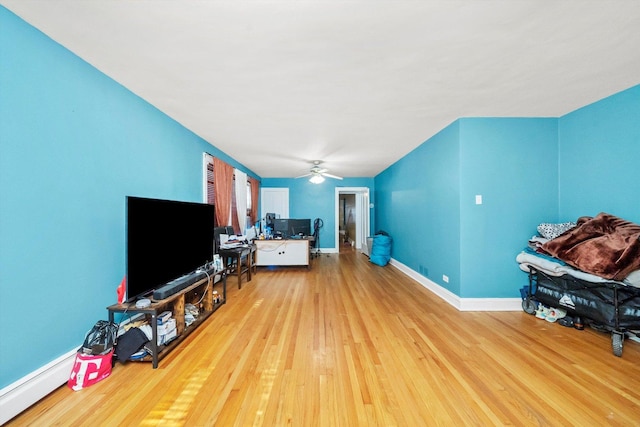 living room featuring ceiling fan, light wood-type flooring, and baseboard heating