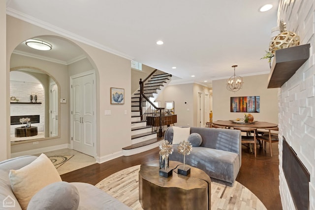 living room with a chandelier, crown molding, a fireplace, and dark wood-type flooring