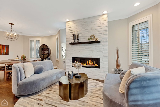 living room with crown molding, a fireplace, light wood-type flooring, and an inviting chandelier