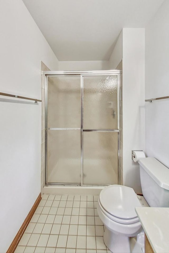 bathroom with tile patterned flooring, vanity, an enclosed shower, and toilet