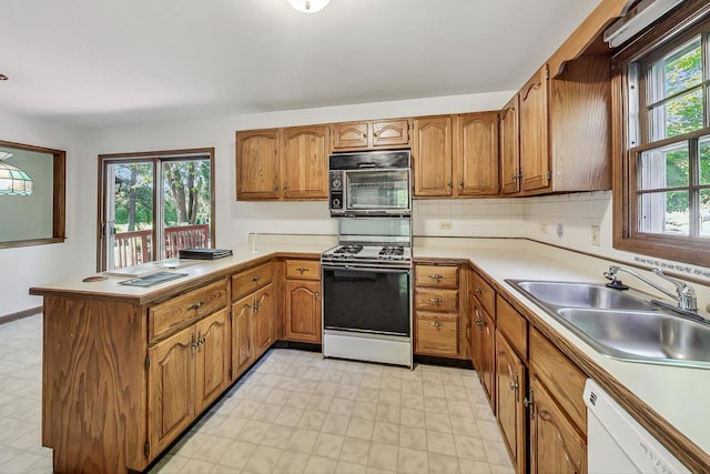 kitchen featuring kitchen peninsula, gas range, sink, and white dishwasher