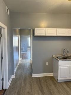 kitchen with white cabinets, dark wood-type flooring, and sink