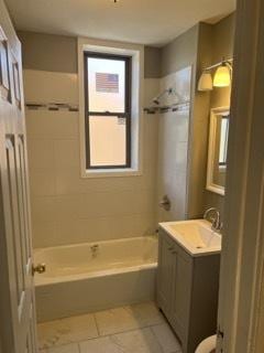 bathroom featuring tile patterned flooring, vanity, and tiled shower / bath combo